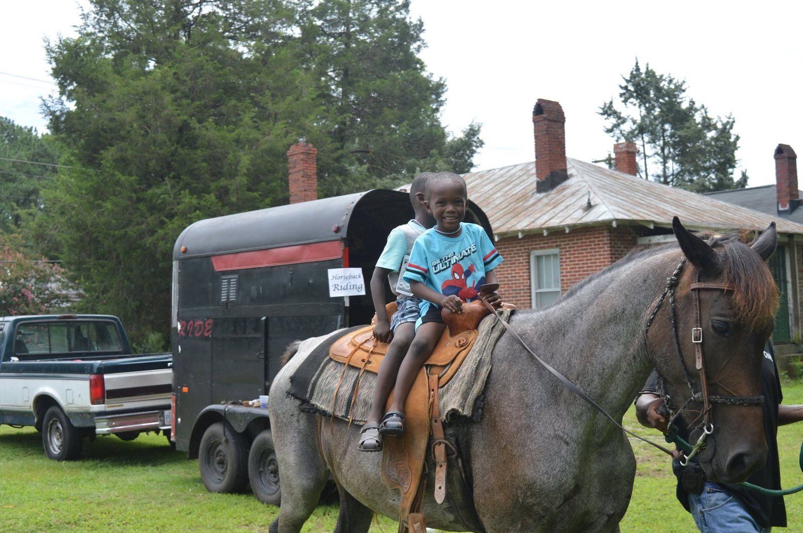 A smiling child enjoying a supervised horseback ride